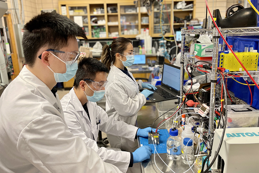 Group of researchers in face masks and lab coats in a lab setting