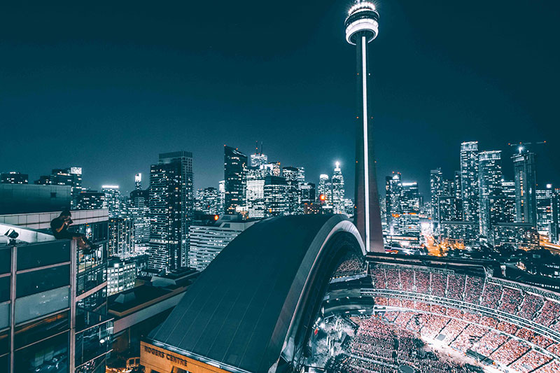 The Rogers Centre with the roof partially open and the Toronto skyline and CN Tower in the background.